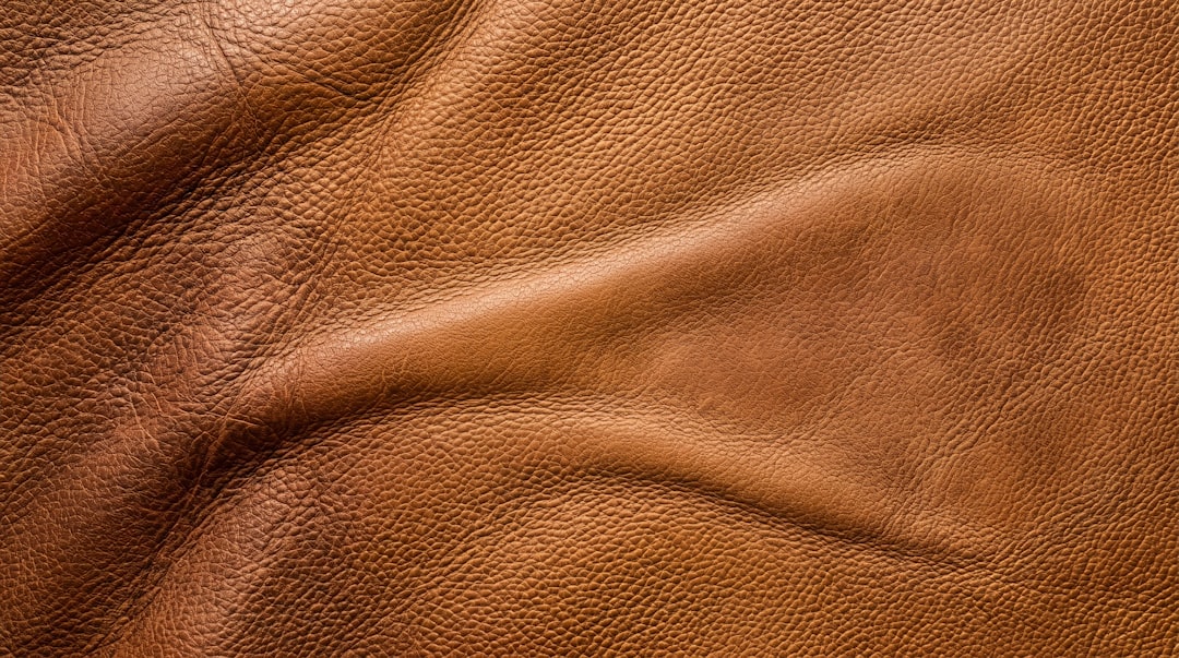 Brown leather surface texture with detailed grain and stitched seam for background